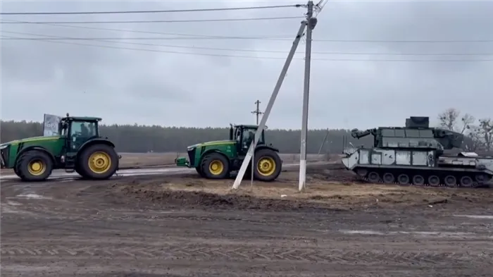 Два трактора буксируют брошенные ракетные установки в Украине.