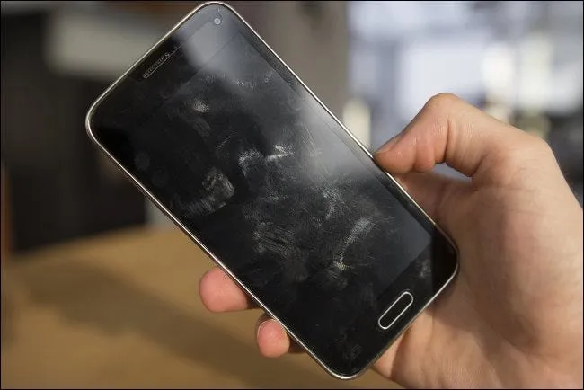 Рука телефон Android с пятнами на экране.