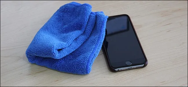 Синяя ткань из микрофибры, сидящая рядом с iPhone. 